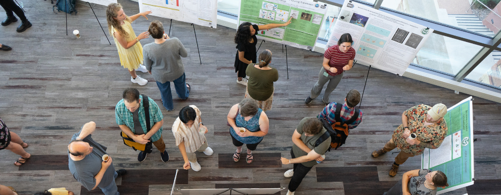 Students present their research to judges at a poster session as seen from above.