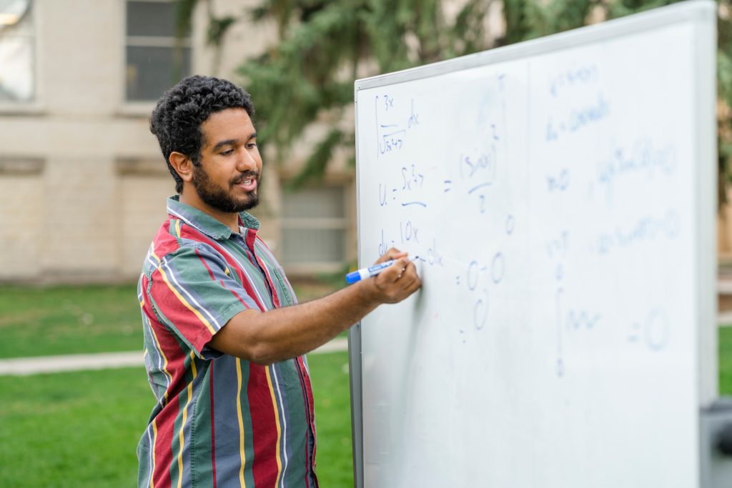 Student does math on a whiteboard outside. 