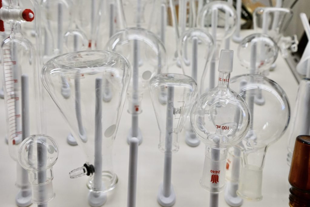 Chemistry flasks sit upside down on a drying rack.